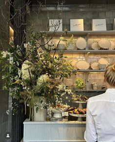 a woman standing in front of a counter filled with flowers