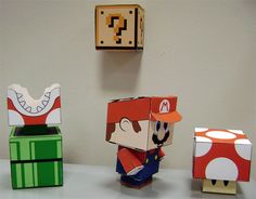 some paper toys that are sitting on a table and one has a mario mushroom figure