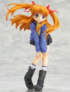 an anime figurine is posed in front of a gray background with long orange hair