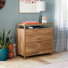 a wooden dresser sitting next to a plant in a living room with blue walls and clock on the wall