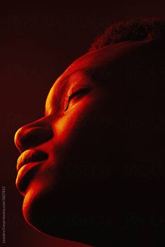 a woman's head with her eyes closed in the dark by an orange light