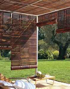 an outdoor area with chairs, tables and wooden shades on the roof over looking grass