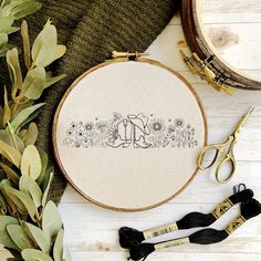 an embroidery kit with scissors, thread and other crafting supplies on a white wooden surface