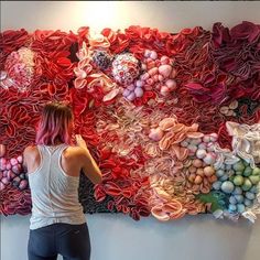 a woman standing in front of a large piece of art made out of paper flowers