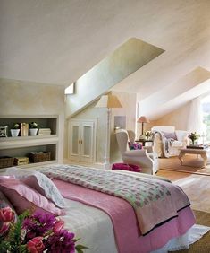 a bedroom with pink and white bedding in the middle of an open floor plan