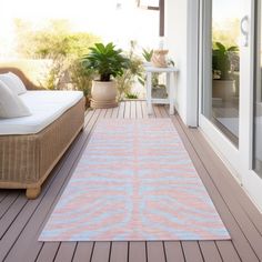 a pink and blue rug sitting on top of a wooden floor next to a white couch