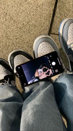 a person with their feet on the ground taking a selfie in front of his cell phone