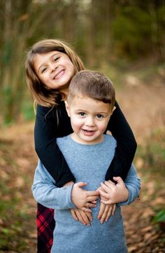 two young children hugging each other in the woods at their family's portrait session