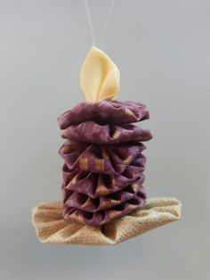 a stack of purple and gold cloths hanging from a string with a white button on top