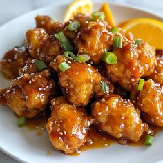 a white plate topped with chicken covered in sesame seeds next to an orange and green garnish