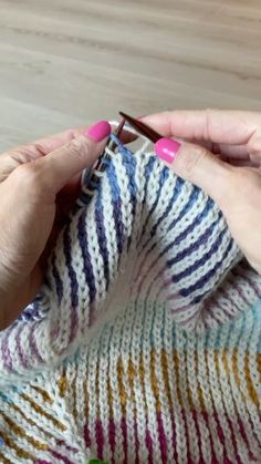 the woman is knitting with her hands on top of the knitted blanket and crochet hooks