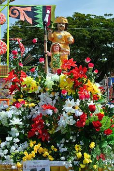 there are many colorful flowers and statues in this parade float, including one with a child on it