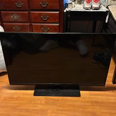 a flat screen tv sitting on top of a wooden floor in front of a dresser