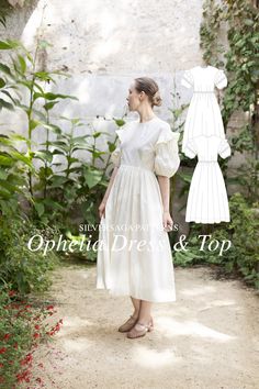 a woman wearing a white dress and sandals standing in front of some flowers with her hands on her hips