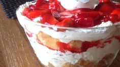 strawberry shortcake with whipped cream and strawberries in a glass dish on a wooden table