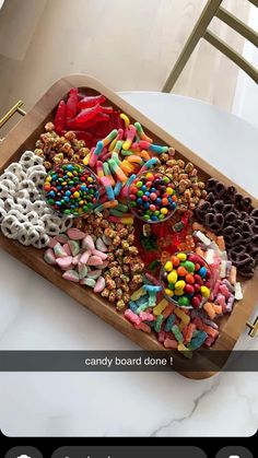 a wooden tray filled with lots of different types of candies on top of a table