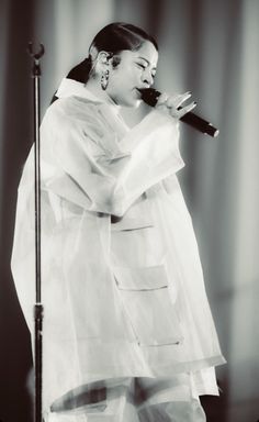 a black and white photo of a woman singing into a microphone