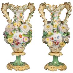 two vases with flowers on them sitting side by side in front of each other