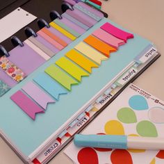 a binder with many different colored papers on it and a pen next to it