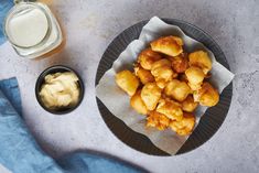 a plate full of fried food next to a glass of milk and a jar of yogurt