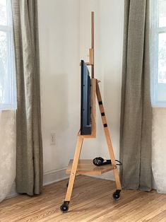 an easel stands in front of a window with curtains and a television on it