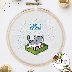 a cross stitch pattern with the words let it snow and an image of a cat on a book