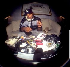 a man sitting on top of a couch next to a table filled with assorted items