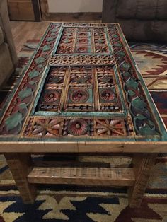 a wooden table with an intricate design on the top and bottom, sitting in front of a couch