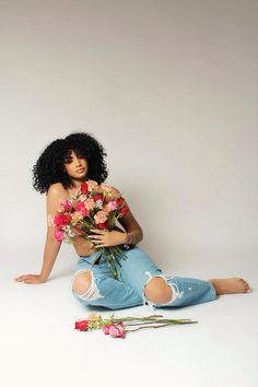 a woman sitting on the ground holding flowers