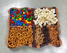 a wooden tray filled with lots of different types of candy and pretzel treats