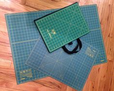 three pieces of green cutting mat sitting on top of each other next to a pair of scissors