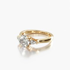 an engagement ring with two pear shaped diamonds on the side, set in yellow gold