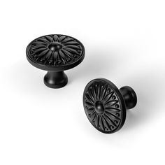 two black cabinet knobs with intricate designs on them