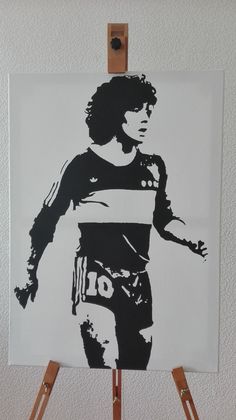 a black and white painting of a soccer player on a easel in front of a wall