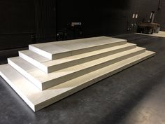 a set of white steps sitting on top of a black floor