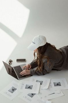 a woman is laying on the floor with her laptop in front of her and papers all around her