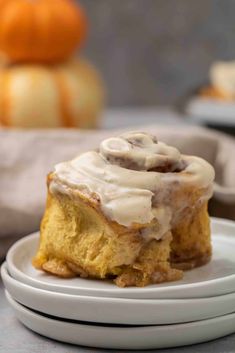 a white plate topped with a cinnamon roll covered in icing on top of a table