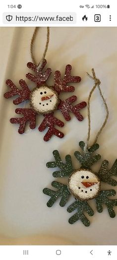 two snowman ornaments hanging from string on a white tablecloth with red and green sequins