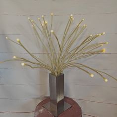 a vase with some lights in it on top of a table next to a wall