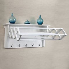 a white shelf with three blue vases on it and two hooks in the middle