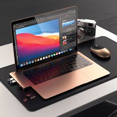 an open laptop computer sitting on top of a desk next to a mouse and camera