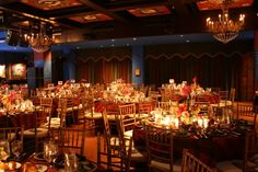 a banquet hall with tables and chairs set up for an event or function, lit by candles