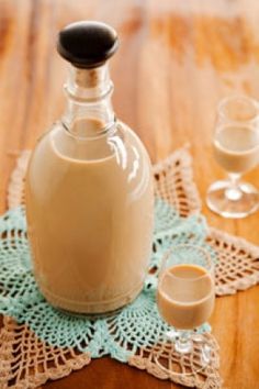 a bottle of vanilla cream sitting on top of a doily next to two glasses