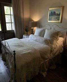 a white bed sitting in a bedroom next to a window