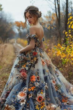 a woman is standing in the woods wearing a dress with flowers and leaves on it