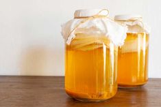 two jars filled with liquid sitting on top of a wooden table