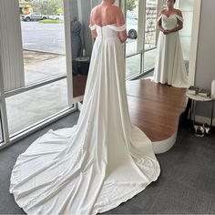 a woman standing in front of a mirror wearing a wedding dress