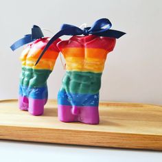 two rainbow colored candy boots are sitting on a wooden tray with a blue ribbon tied around the boot