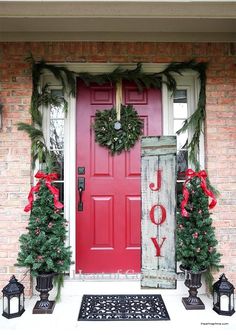 a red front door decorated for christmas with wreaths and lights