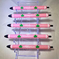 four personalized pens with holly leaves on them are lined up in a clear holder